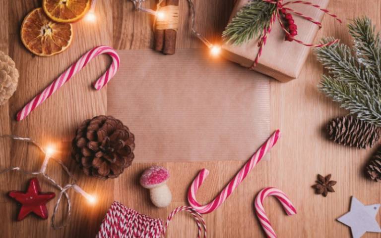 Candy canes, pine cones and presents wrapped in brown paper and string on a wooden table.