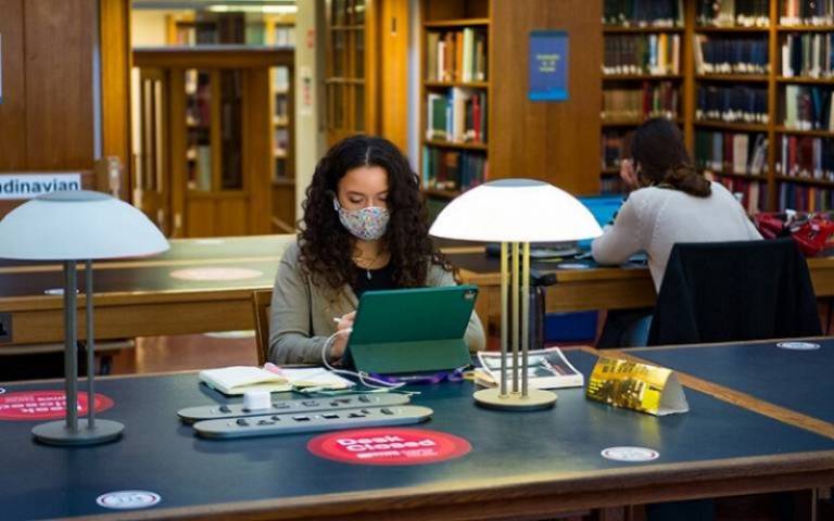 Student studying in the library wearing a mask