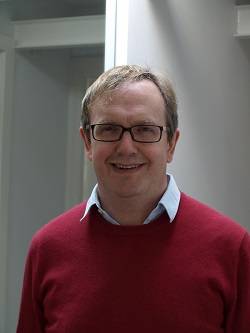 Chris Watkins - a man wearing glasses in a red jumper smiling at the camera