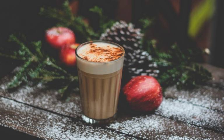 Photo showing a wooden bench, pine cones, and a hot festive drink