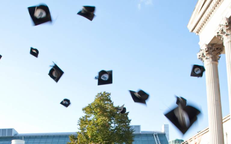 Mortarboards thrown in the air in front of the Wilkins Building