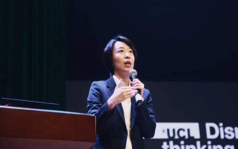 UCL alumna Linda Zhang speaking on stage at event