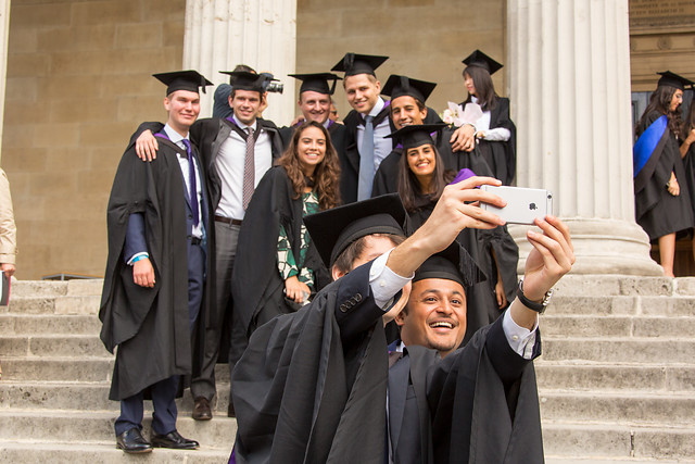 Group of UCL students of diverse ethnic background taking photographs of themselves at a graduation ceremony on the steps of the UCL Portico in 2015 