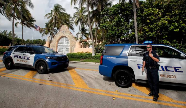 Photo showing two patrol cars and a police officer at the gates of Donald Trump's Mar-a-Lago residence