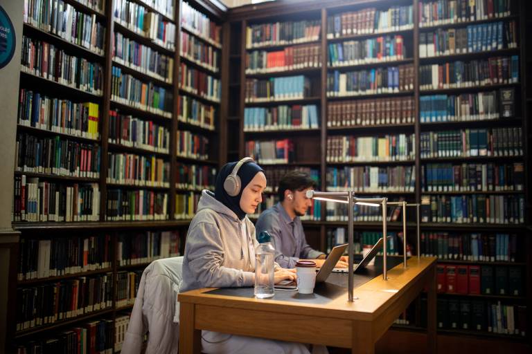 Two UCL students studying on laptops in the Main Library