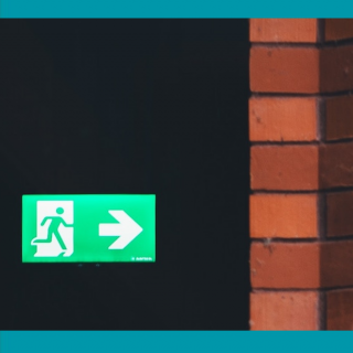 Composite image showing an exit sign against the background of a dark space and detail of a brick wall