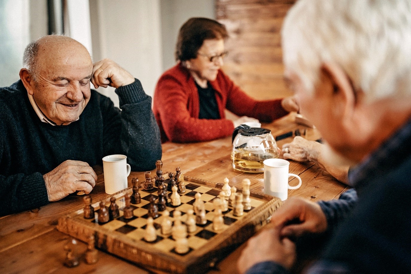 Two people playing chess at wooden table