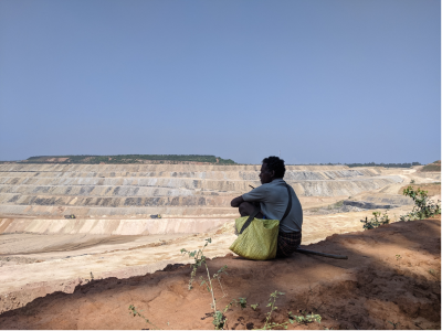 A man sat on the edge of a quarry looking out