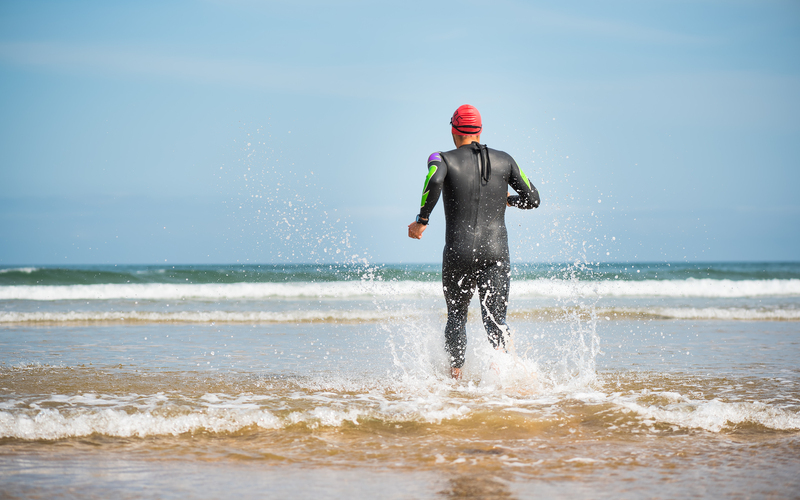Man entering the water in a wetsuit at the beach
