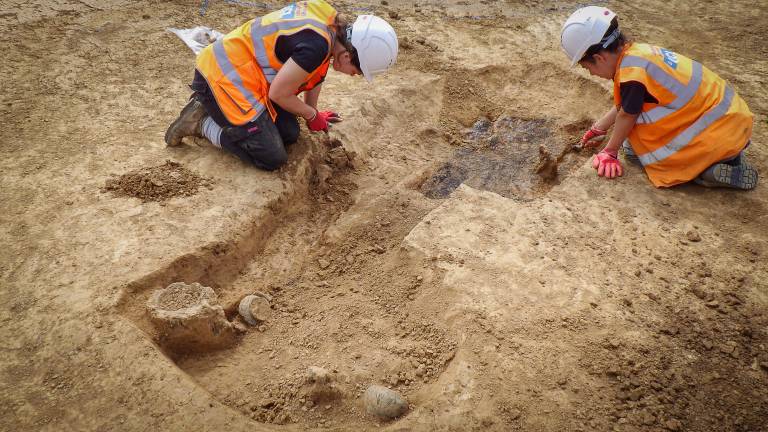 Two archaeologists digging on site.