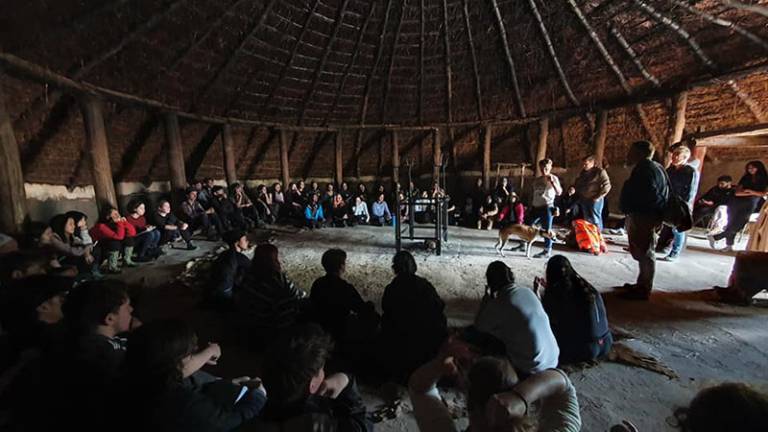Large group of people (students) sitting around the sides of a large roundhouse