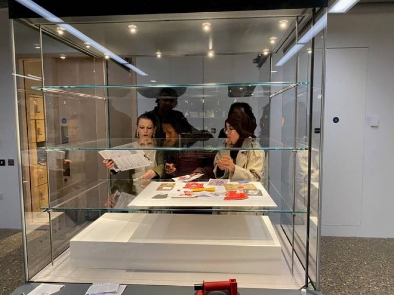 A group of five young people standing behind a museum exhibition/display case