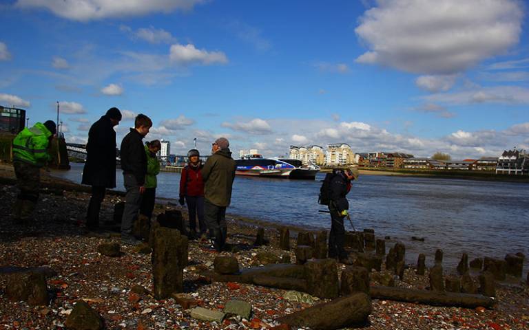 Group of people standing beside a river, some in yellow high-vis jackets
