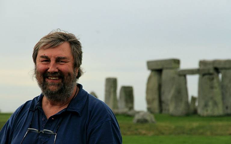 Picture of a bearded man standing outside in front of an ancient monument (Stonehenge)