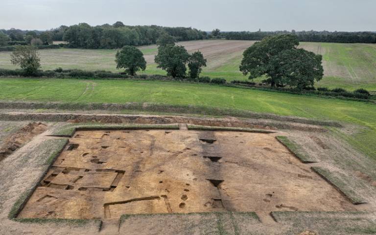 An archaelogical site in a field showing the archaeological remains including the probable temple or cult house (left hand side) and boundary ditch (centre)