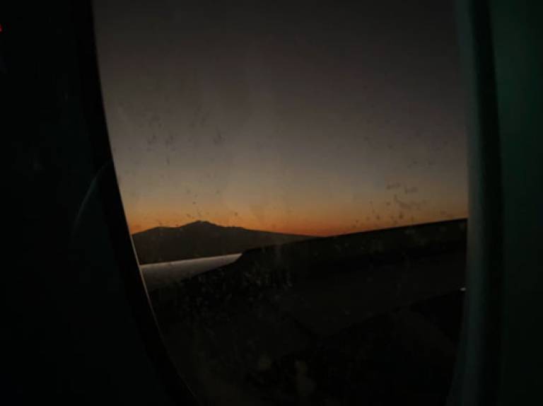 View out of an airplane window of a sunrise in the distance