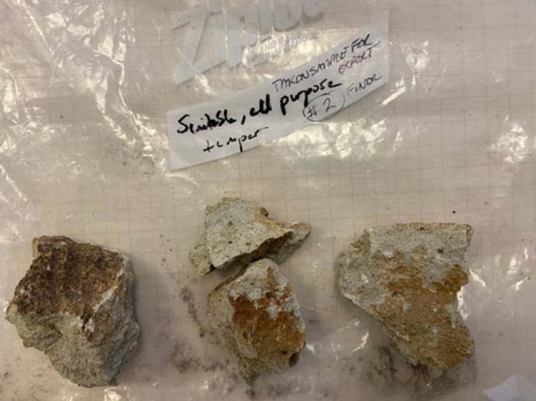 Four fragments of ceramic temper (grey/brown) displayed on a plastic sample bag