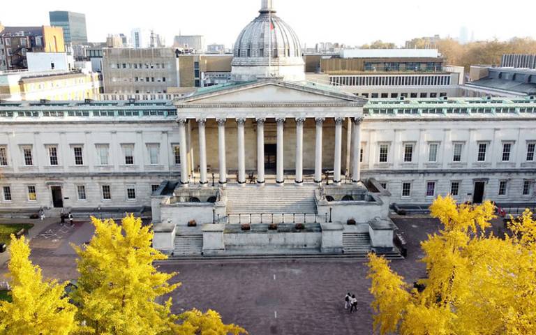 Overhead image of a large light-coloured stone building with portico and dome and yellow flowering trees in the foreground (© Ross Turner – The London Drone Company)