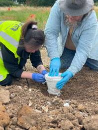 Conservation work being undertaken on site at UCL Norton Fieldschool by two people, one in a yellow high-vis best and the other wearing a blue jacket, both wearing blue gloves