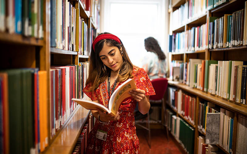 Student looking at a book in a library