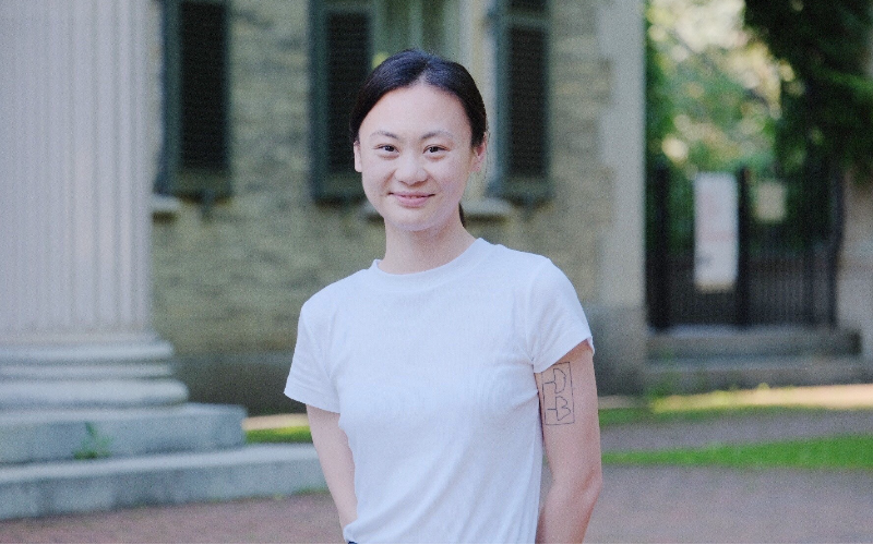 an Asian woman in a white tshirt smiles at the camera
