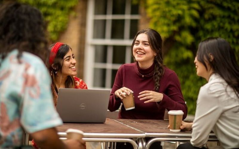 A group of students laugh and talk on UCL main campus.