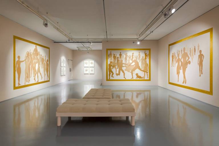 an exhibition space with gold framed images of people
