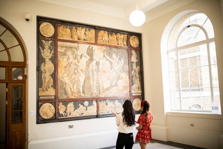 two women look at a piece of art on the wall