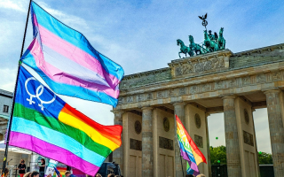pride flag next to a monument with a statue of 4 horses on top