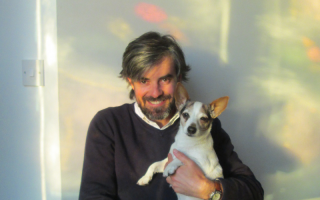 a man holding a dog smiles at the camera