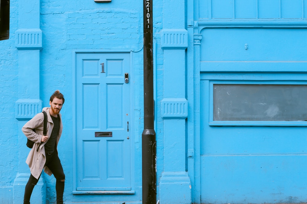Man walking past blue house in London