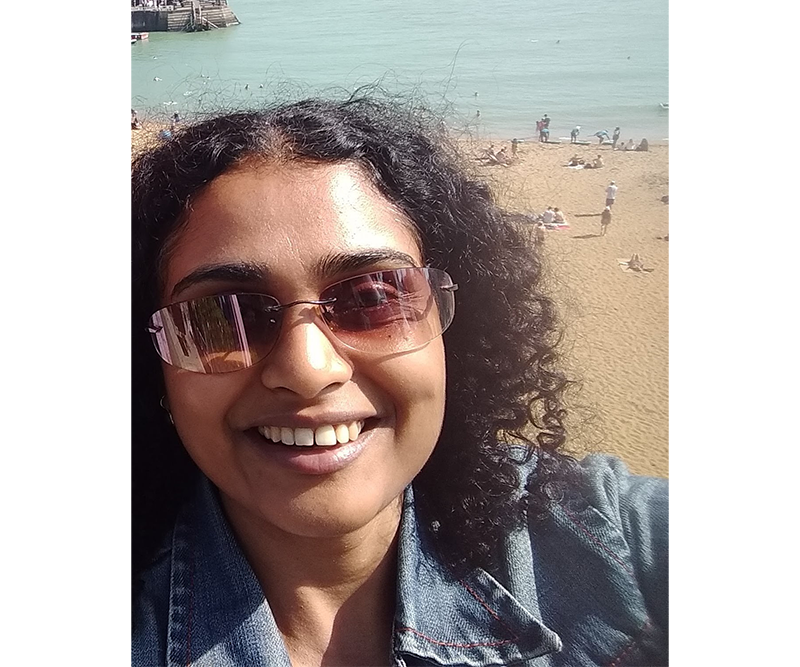 Selfie of Aparna with the sea in the background.