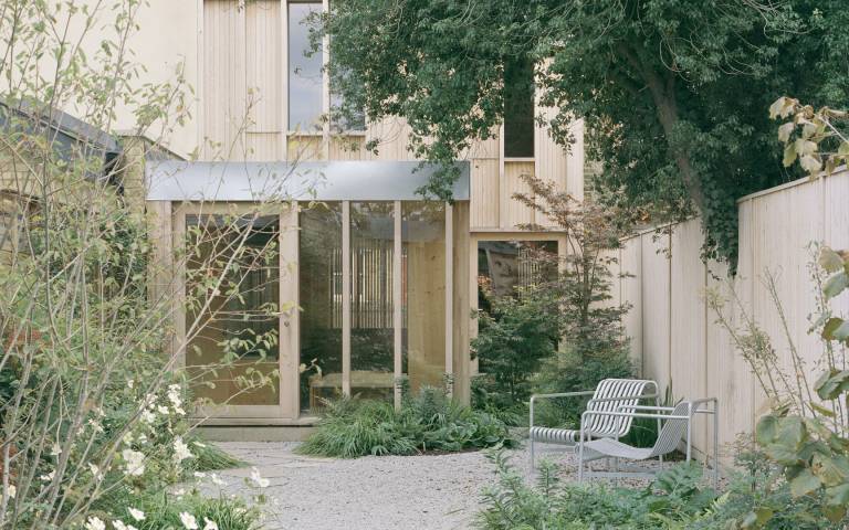 Image: rear courtyard of Spruce House and Studio, with plants in the foreground and the back facade of the house in the background