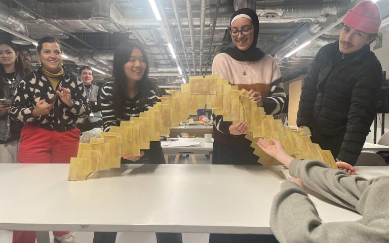 Students gather around a bridge constructed from flat lasagne pasta sheets