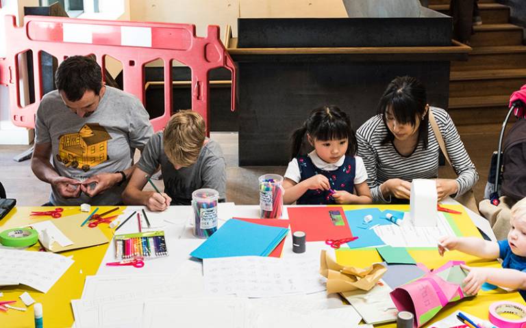 The Bartlett Summer Show Family Day 2018. Two children and their parents are sitting at a table doing arts and crafts.