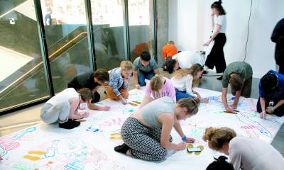 young people drawing maps on a large piece of paper on the floor
