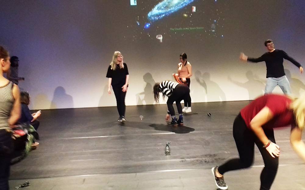 People performing in front of a screen showing the earth and space