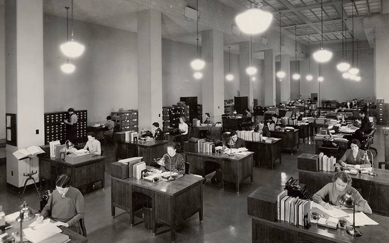 An old photograph of women working at desks with books