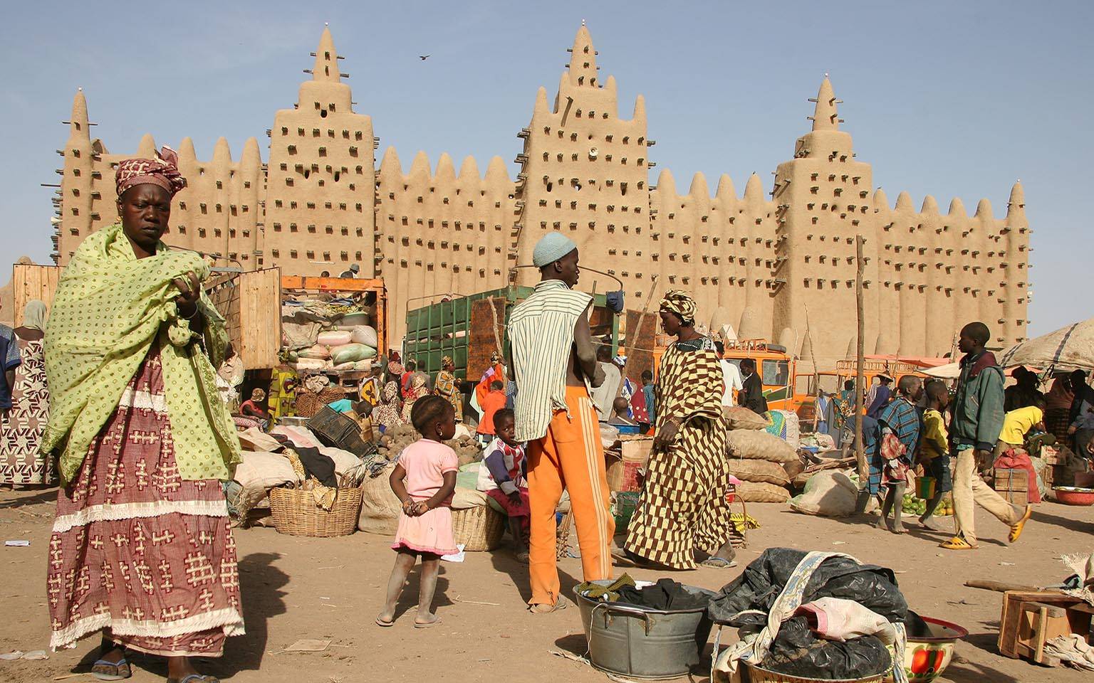 Mosque in Djenne with families in a market place in the foreground