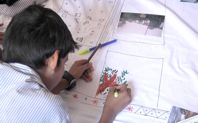 A child draws on fabric in his school in Mumbai