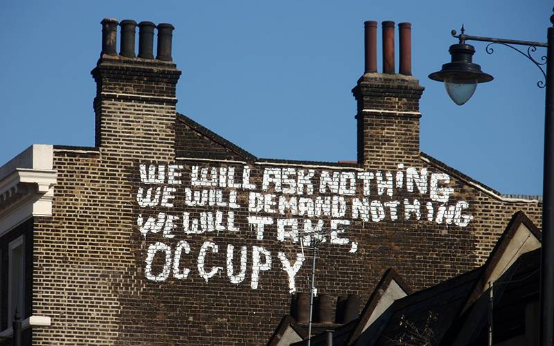 'We will ask nothing, demand nothing, we will take, occupy' painted in white on a brick building