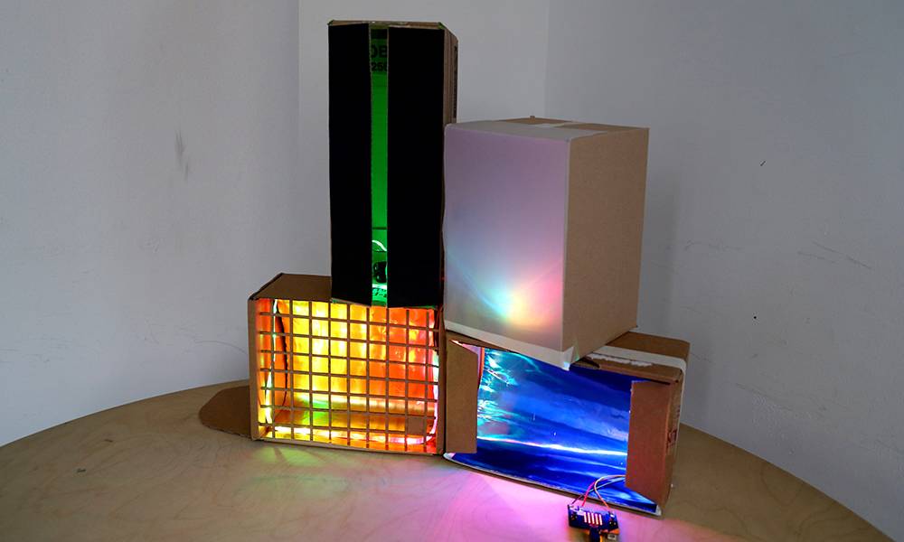 cardboard boxes cut out with coloured lights inside
