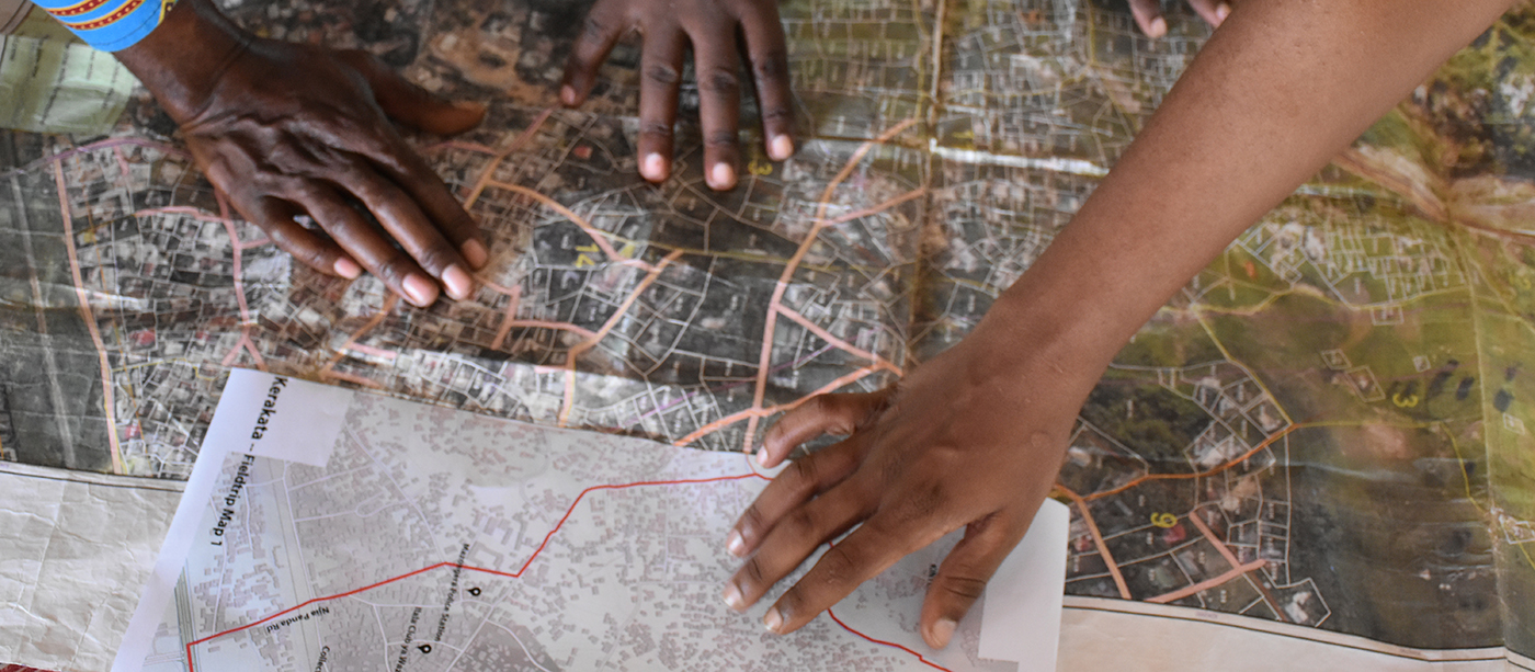 Image on hands pointing to various places on a map of Dar es Salaam, Tanzania