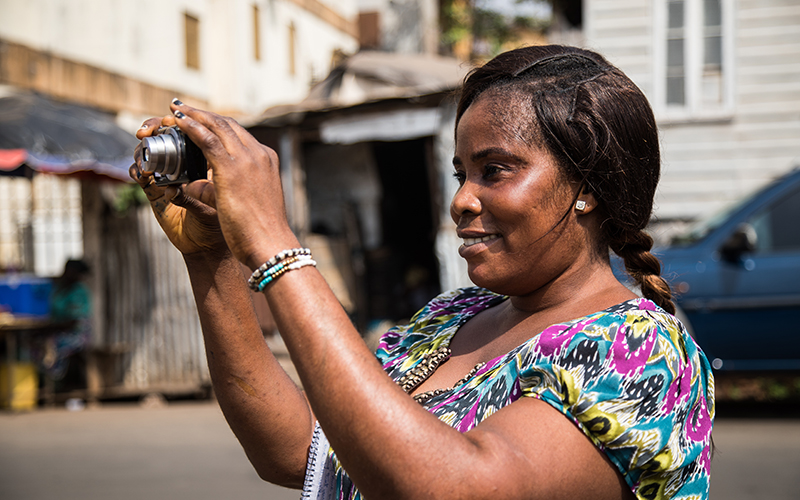 A participant takes a photography as part of a participatory photography workshop in Freetown, Sierra Leone, co-facilitated between DPU and SLURC