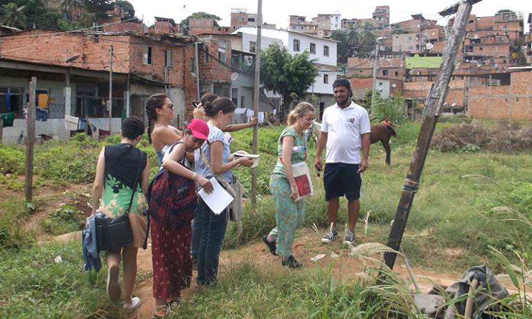 Students and projects partners standing in a field of grass, surrounded by settlements