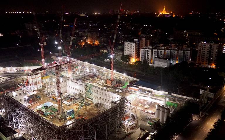 Yangon by night with construction and distant temple