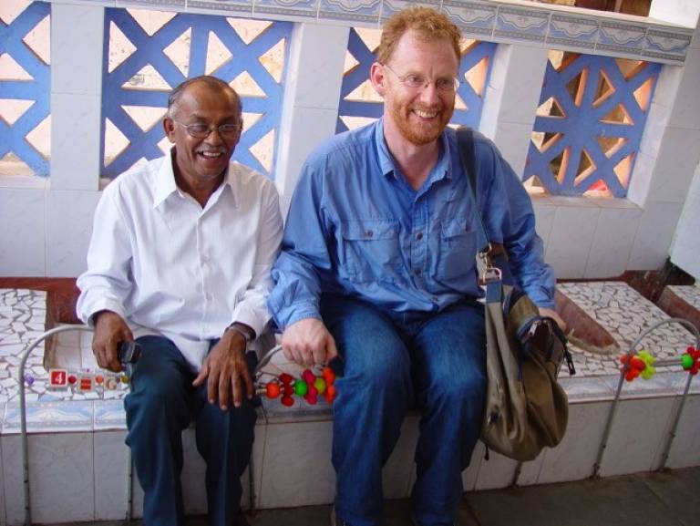 Two men sitting on a bench and smiling at the camera