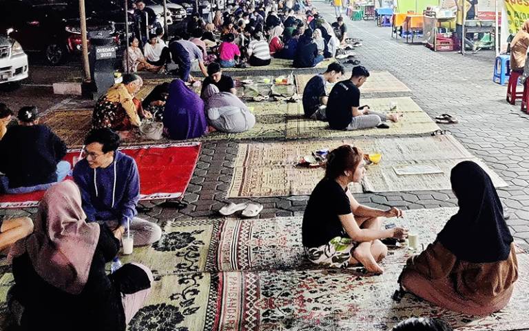 A group of people sitting outside on rugs