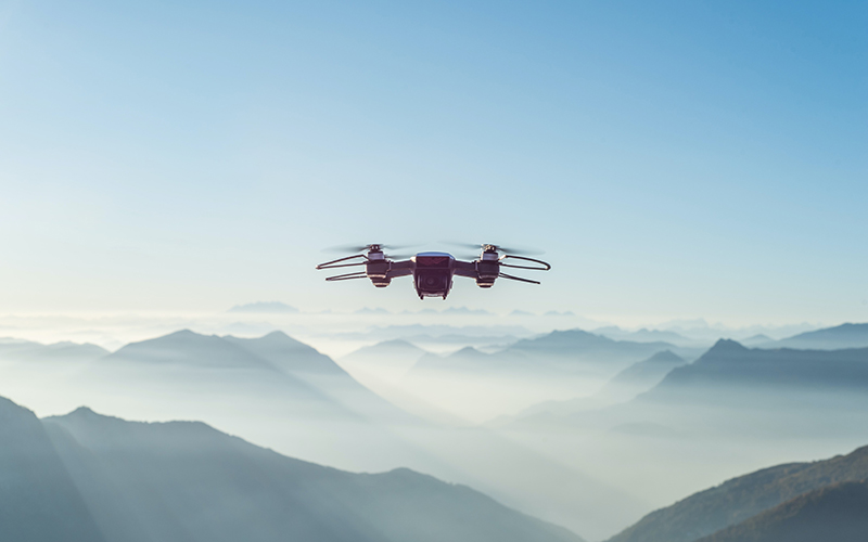 Drone flying through sky with mountains in background