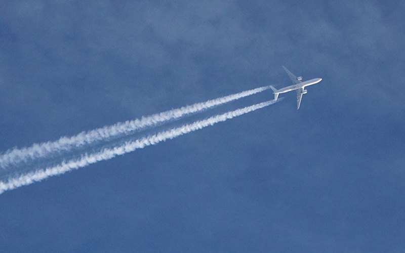 Plane in the sky leaving visible contrails